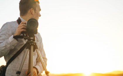 Photographer standing next to a tripod with camera attached