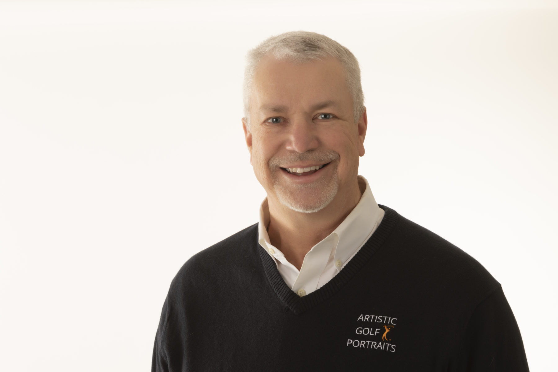 Headshot Photography image of Doug Mattice. CEO of Doug Mattice Photography and Marketing. He is smiling has grey hair and a goatee. He is wearing a black sweater over a white shirt.